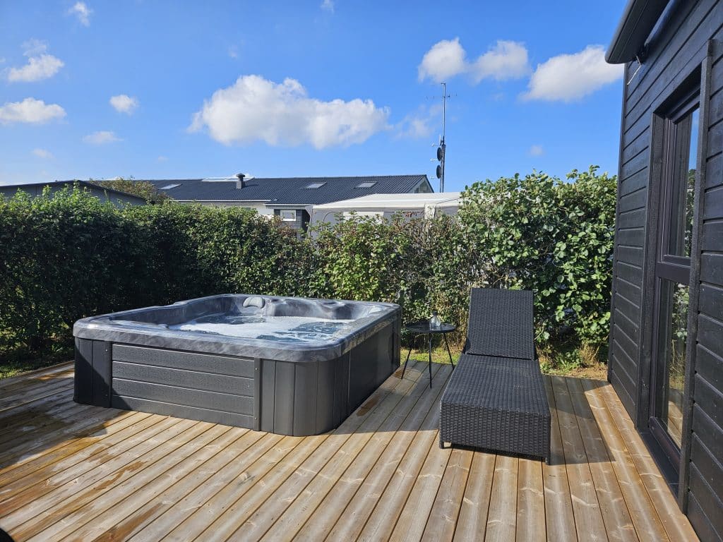 Terrasse med udendørs spa og solseng i hotelhytte med spa