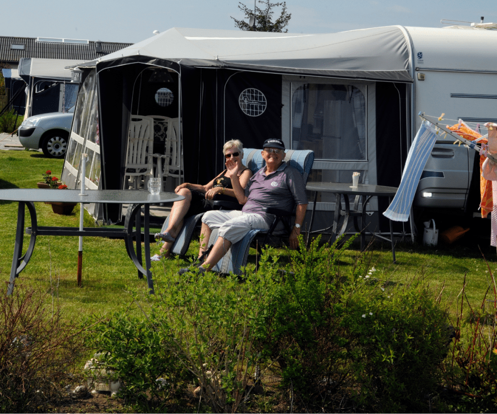 Seniorer hygger sig foran deres campingvogn med fortelt