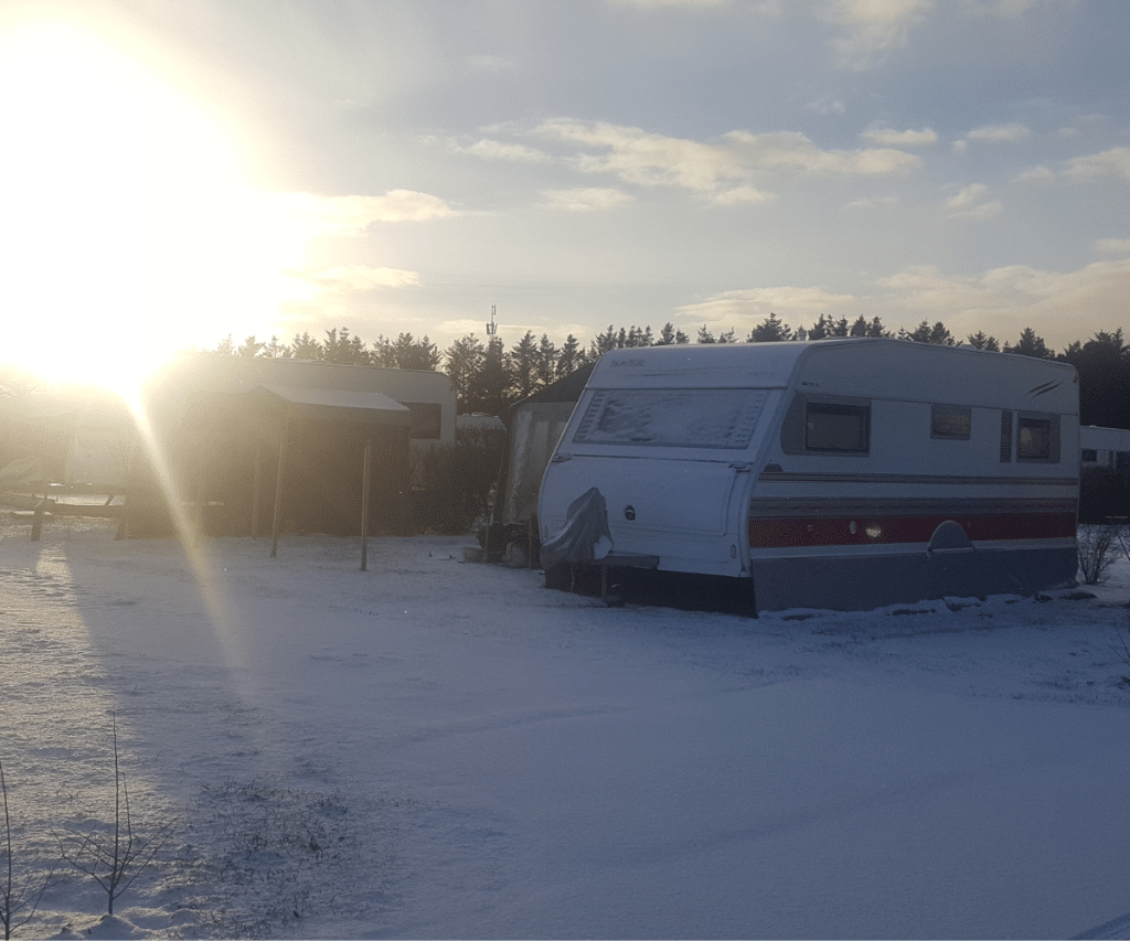 Snedækket campingvogn med solen i baggrunden på Løkken Klit